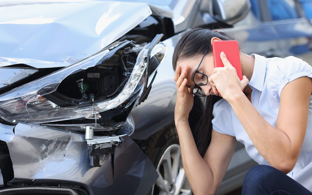 Sad woman talking on cell phone near wrecked car. Female driver concept